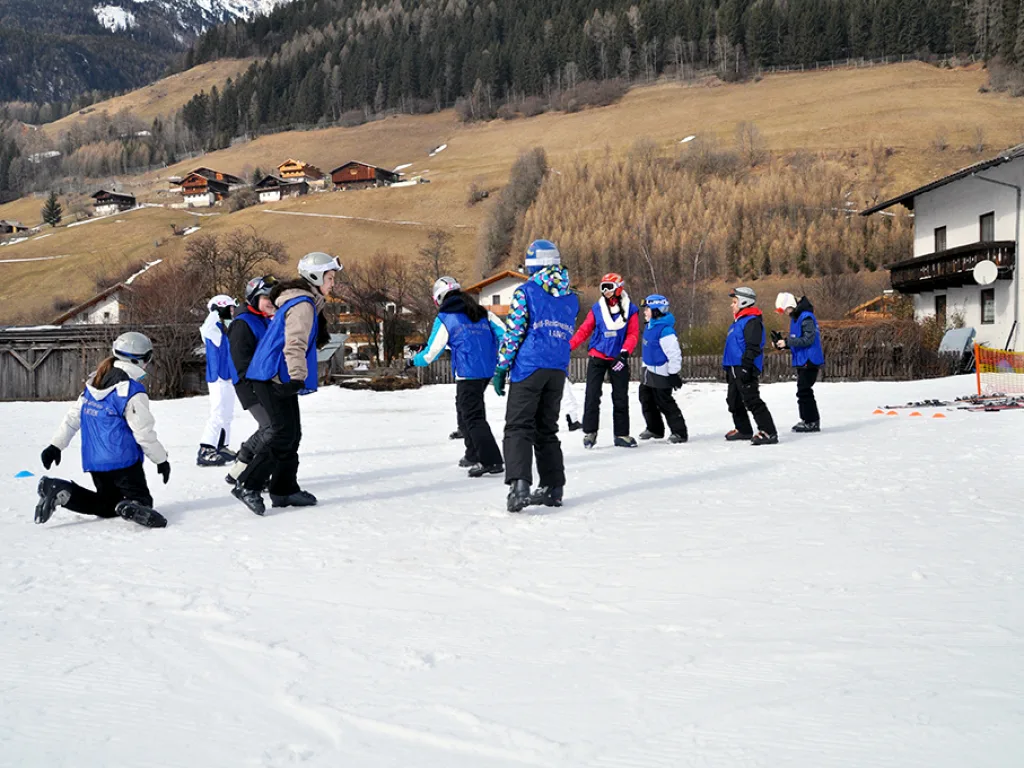 Skigruppe folgt der Lehrkraft über die Übungswiese.